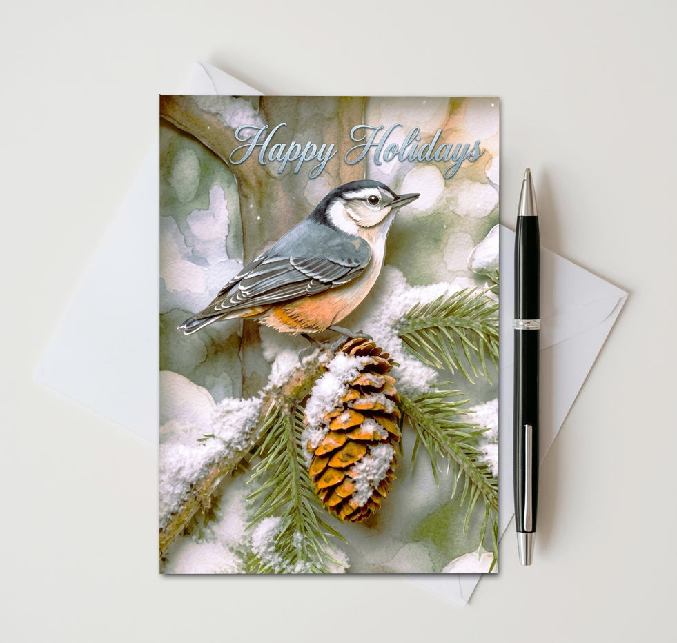 Happy Holidays nuthatch card with snow-covered pinecone and evergreen branches, beside an envelope and pen
